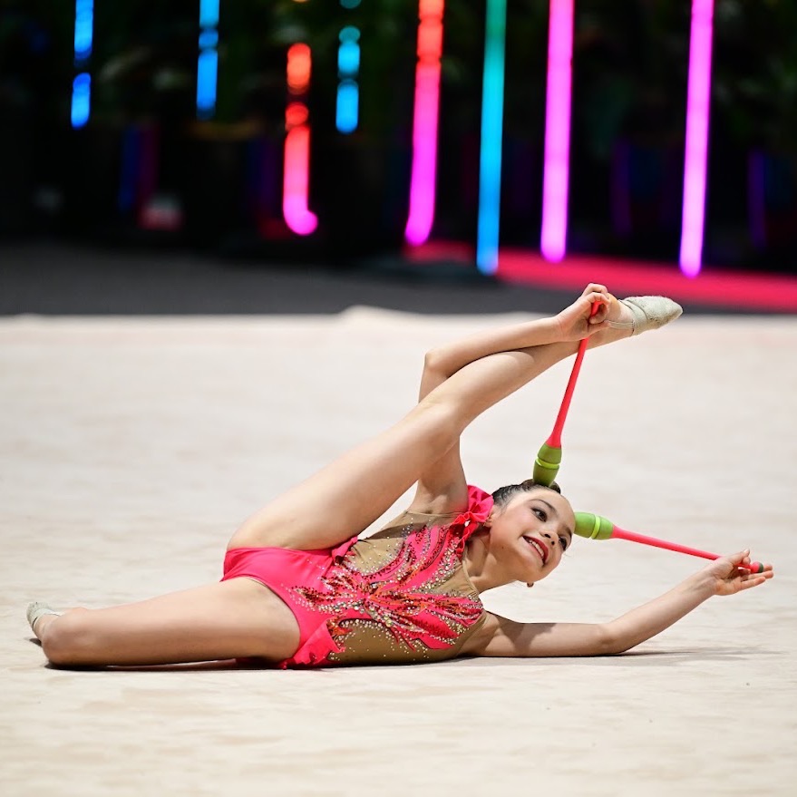 Rhythmic gymnast performing with clubs